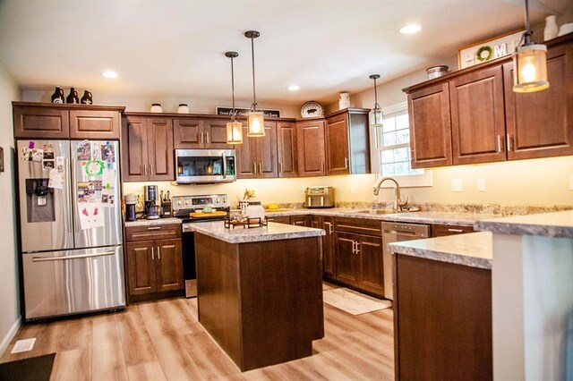 20083 Southview Dr, Carlyle, IL 62231 - kitchen featuring appliances with stainless steel finishes, a sink, light wood-type flooring, a center island, and decorative light fixtures