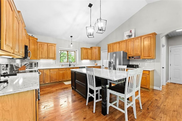 2347 Callaway Fork Rd, Defiance, MO 63341 - kitchen with stainless steel fridge with ice dispenser, a kitchen island, decorative backsplash, light stone counters, and arched walkways