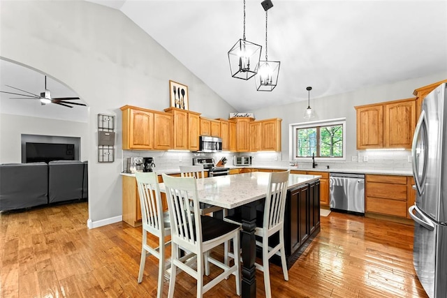 2347 Callaway Fork Rd, Defiance, MO 63341 - kitchen featuring appliances with stainless steel finishes, a sink, a center island, backsplash, and light wood finished floors