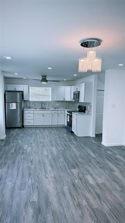 1204 Griefield Pl, Pagedale, MO 63133 - kitchen with appliances with stainless steel finishes, white cabinetry, baseboards, dark wood-style flooring, and decorative backsplash