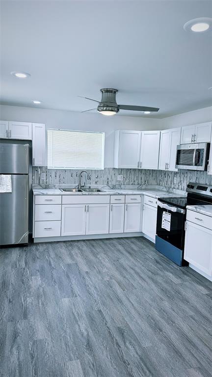 1204 Griefield Pl, Pagedale, MO 63133 - kitchen with stainless steel appliances, a sink, white cabinetry, tasteful backsplash, and light countertops