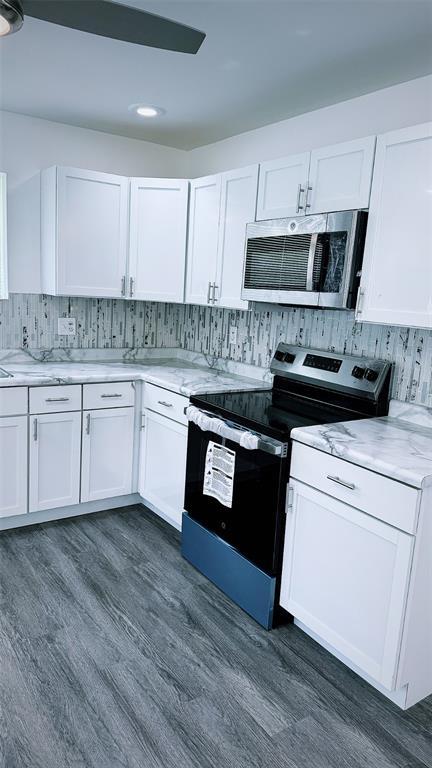 1204 Griefield Pl, Pagedale, MO 63133 - kitchen with stainless steel appliances, white cabinetry, backsplash, dark wood-style floors, and recessed lighting