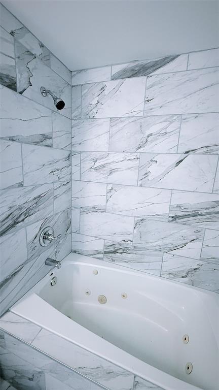 1204 Griefield Pl, Pagedale, MO 63133 - bathroom featuring a combined bath / shower with jetted tub and marble look tiles