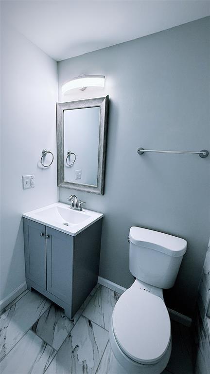 1204 Griefield Pl, Pagedale, MO 63133 - bathroom featuring vanity, toilet, baseboards, and marble look tile flooring