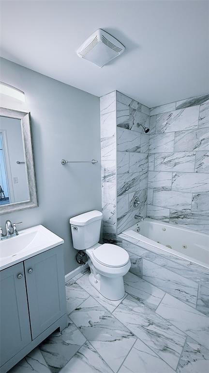 1204 Griefield Pl, Pagedale, MO 63133 - bathroom featuring marble finish floors, vanity, toilet, and a combined bath / shower with marble appearance