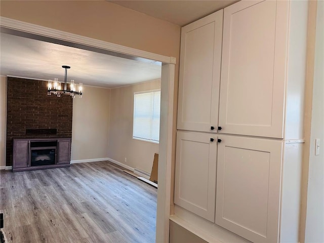 9715 Millburn Dr, Saint Louis, MO 63136 - unfurnished living room featuring light wood-style flooring, a chandelier, baseboards, and a large fireplace