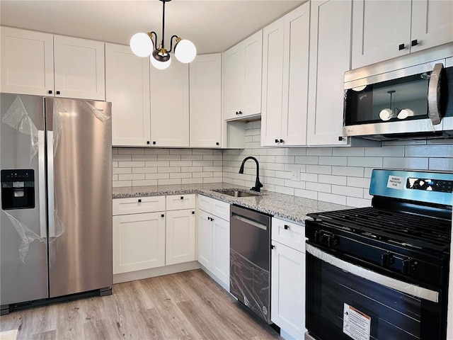 9715 Millburn Dr, Saint Louis, MO 63136 - kitchen with appliances with stainless steel finishes, a sink, white cabinetry, light stone counters, and tasteful backsplash
