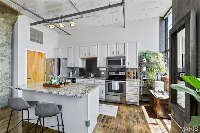 2020 Washington Ave Unit 210, Saint Louis, MO 63103 - kitchen with appliances with stainless steel finishes, a high ceiling, dark wood-type flooring, backsplash, and a breakfast bar area