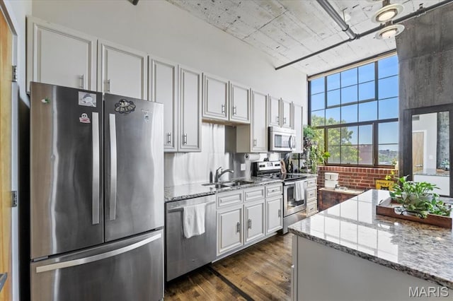 2020 Washington Ave Unit 210, Saint Louis, MO 63103 - kitchen with stainless steel appliances, tasteful backsplash, dark wood-style flooring, light stone counters, and a towering ceiling