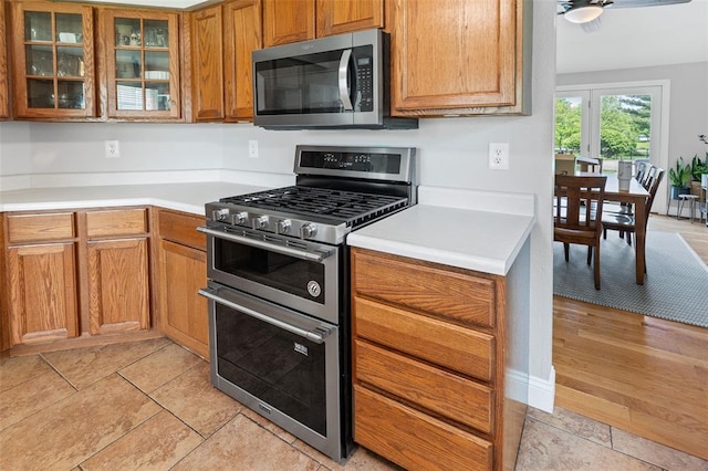 21 Sunny Dale Ct, Glen Carbon, IL 62034 - kitchen featuring appliances with stainless steel finishes, light countertops, glass insert cabinets, brown cabinetry, and light tile patterned flooring