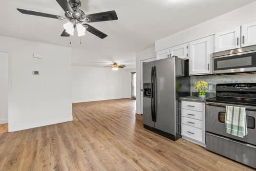 352 Della Dr, Saint Peters, MO 63376 - kitchen with appliances with stainless steel finishes, white cabinets, a ceiling fan, light wood finished floors, and backsplash
