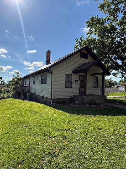 133 S Walnut St, Perryville, MO 63775 - view of front of house featuring covered porch, a front lawn, a chimney, and central AC