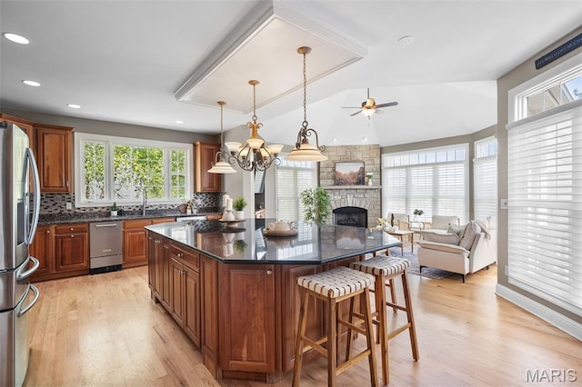4516 Austin Point Ct, Saint Charles, MO 63304 - kitchen with appliances with stainless steel finishes, open floor plan, a ceiling fan, a kitchen breakfast bar, and a stone fireplace