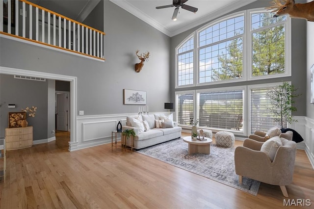 4516 Austin Point Ct, Saint Charles, MO 63304 - living room featuring a towering ceiling, ornamental molding, a ceiling fan, wood finished floors, and a wainscoted wall