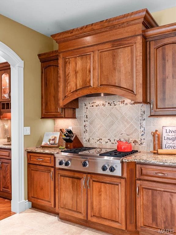 4516 Levis Ln, Godfrey, IL 62035 - kitchen with stainless steel gas cooktop, brown cabinets, arched walkways, and light stone countertops