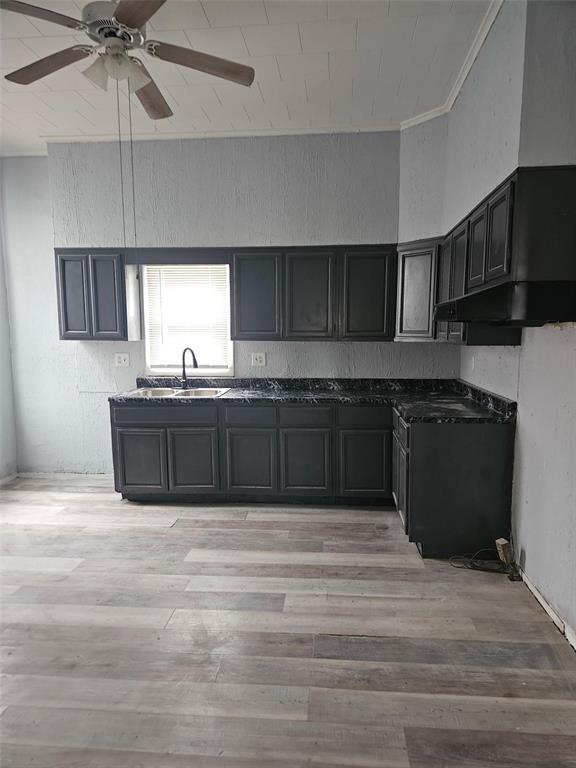 633 4th St, Carrollton, IL 62016 - kitchen with ornamental molding, ceiling fan, light wood-type flooring, dark countertops, and a sink