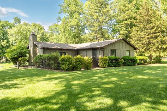 11 Glen Hollow Rd, Glen Carbon, IL 62034 - view of property exterior featuring a chimney, a lawn, board and batten siding, and roof with shingles