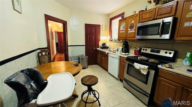5044 Louisiana Ave, Saint Louis, MO 63111 - kitchen with stainless steel appliances, tile walls, light countertops, a wainscoted wall, and a sink