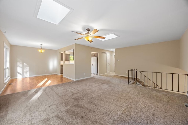 243 Mill Run Ln, Saint Peters, MO 63376 - unfurnished living room with a skylight, light colored carpet, a ceiling fan, and baseboards