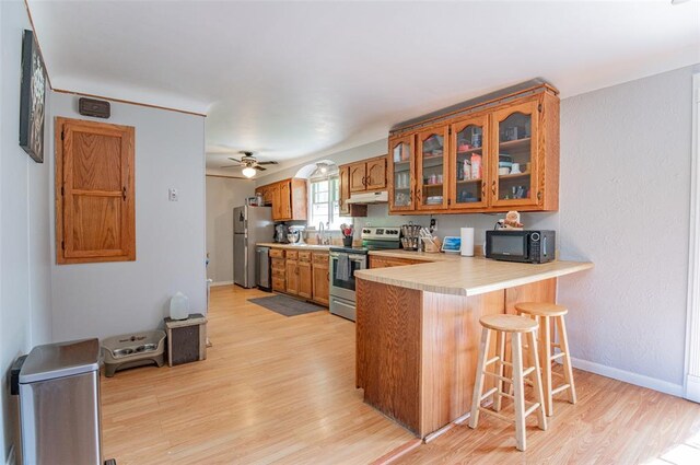 300 N Alvarado Ave, Belle, MO 65013 - kitchen featuring stainless steel appliances, brown cabinetry, under cabinet range hood, light wood-type flooring, and light countertops