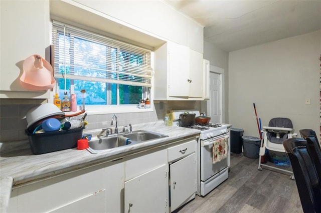 8033 Winfield Ave, Saint Louis, MO 63114 - kitchen with white gas range oven, wood finished floors, a sink, white cabinetry, and plenty of natural light