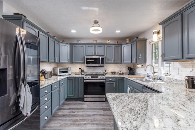 2115 Tower Rd, Lebanon, MO 65536 - kitchen with stainless steel appliances, a sink, light wood-style flooring, light stone countertops, and backsplash
