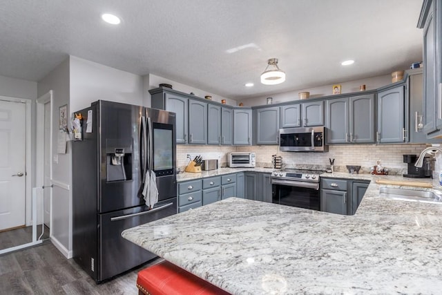 2115 Tower Rd, Lebanon, MO 65536 - kitchen featuring appliances with stainless steel finishes, a sink, a peninsula, light stone counters, and dark wood finished floors
