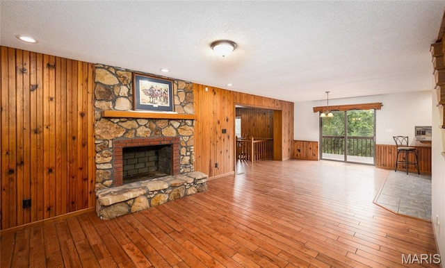 13399 S US Highway 63, Rolla, MO 65401 - unfurnished living room featuring wooden walls, a textured ceiling, a stone fireplace, and hardwood / wood-style flooring