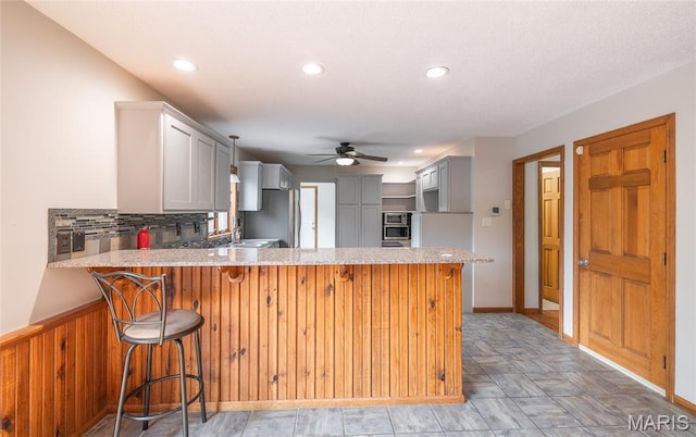 13399 S US Highway 63, Rolla, MO 65401 - kitchen with a ceiling fan, freestanding refrigerator, a peninsula, wall oven, and light stone countertops