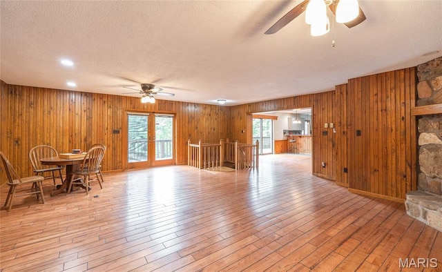 13399 S US Highway 63, Rolla, MO 65401 - living area featuring ceiling fan, a textured ceiling, wood walls, healthy amount of natural light, and light wood finished floors