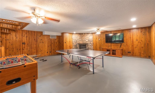 13399 S US Highway 63, Rolla, MO 65401 - playroom featuring finished concrete floors, ceiling fan, wood walls, a stone fireplace, and a textured ceiling