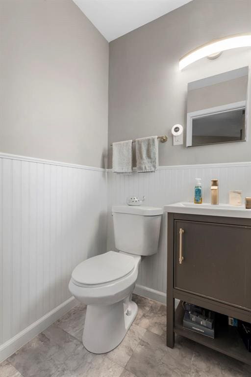 1090 Apache Dr, Florissant, MO 63033 - bathroom with toilet, vanity, baseboards, and wainscoting