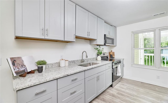 2613 Hillsboro Valley Park Rd, High Ridge, MO 63049 - kitchen with appliances with stainless steel finishes, a sink, light wood finished floors, light stone counters, and baseboards