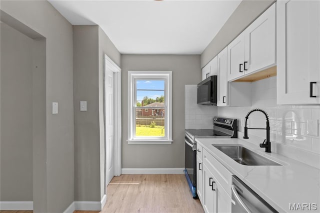 8364 Fullerton Ave, University City, MO 63132 - kitchen featuring stainless steel appliances, decorative backsplash, white cabinets, light wood-style flooring, and light stone counters