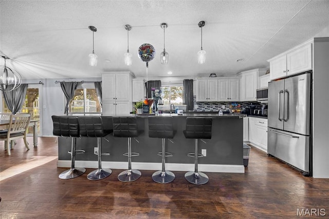 2850 S Hwy W, Winfield, MO 63389 - kitchen with stainless steel appliances, dark countertops, a kitchen bar, white cabinetry, and dark wood-type flooring