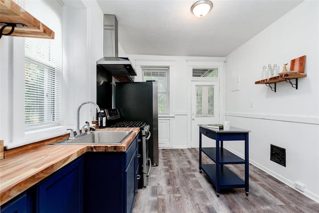 4219 Red Bud Ave, Saint Louis, MO 63115 - kitchen with blue cabinetry, wood counters, a sink, gas range, and wood finished floors