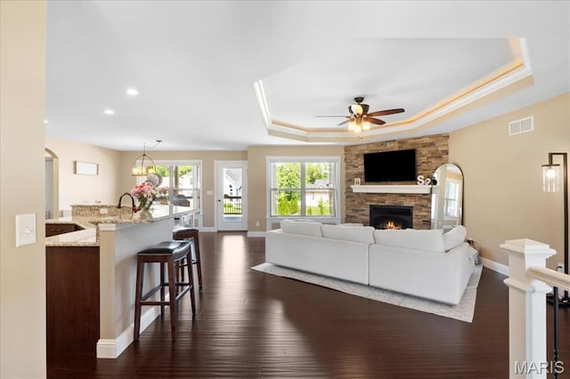 8743 Cardinal Creek Dr, Saint Jacob, IL 62281 - living area featuring a fireplace, a raised ceiling, baseboards, ceiling fan, and dark wood-style flooring