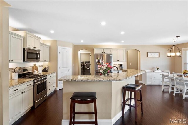 8743 Cardinal Creek Dr, Saint Jacob, IL 62281 - kitchen featuring appliances with stainless steel finishes, independent washer and dryer, arched walkways, dark wood-type flooring, and a kitchen breakfast bar