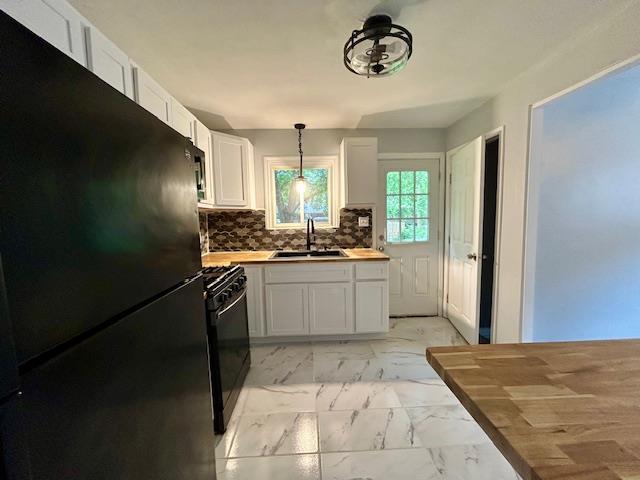 1157 June Ave, Saint Louis, MO 63138 - kitchen with black appliances, a sink, light marble finish flooring, white cabinetry, and hanging light fixtures