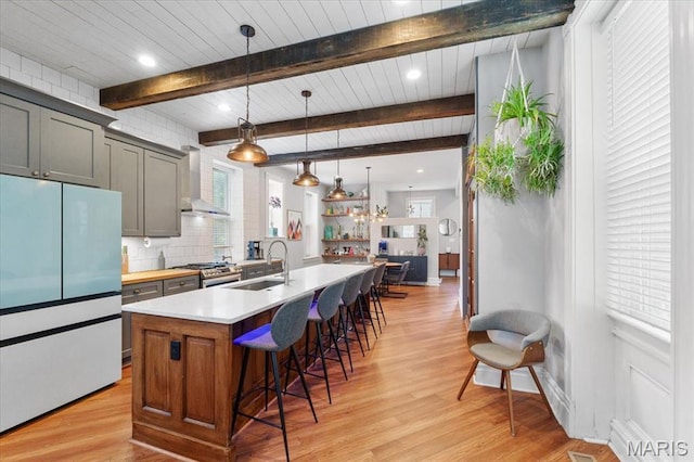 2000 Withnell Ave, Saint Louis, MO 63118 - kitchen featuring freestanding refrigerator, wall chimney exhaust hood, gas stove, a sink, and a kitchen breakfast bar