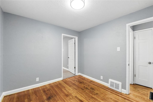 1901 Bainbridge Dr, Saint Louis, MO 63133 - unfurnished room with wood finished floors, baseboards, a textured ceiling, and a textured wall