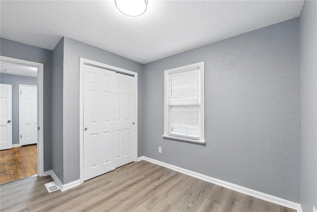 1901 Bainbridge Dr, Saint Louis, MO 63133 - unfurnished bedroom featuring light wood-type flooring, a closet, and baseboards