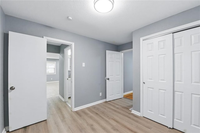 1901 Bainbridge Dr, Saint Louis, MO 63133 - unfurnished bedroom featuring light wood-style floors, baseboards, a closet, and a textured ceiling