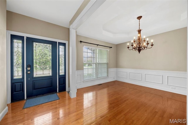 102 Riparian Dr, Ofallon, MO 63368 - entrance foyer with a chandelier, light wood-type flooring, wainscoting, a raised ceiling, and a decorative wall