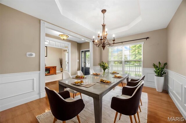 102 Riparian Dr, Ofallon, MO 63368 - dining area featuring a chandelier, wainscoting, light wood-style flooring, a tray ceiling, and a decorative wall