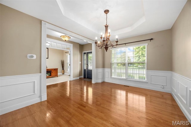 102 Riparian Dr, Ofallon, MO 63368 - unfurnished dining area with a chandelier, a raised ceiling, healthy amount of natural light, a wainscoted wall, and light wood-type flooring