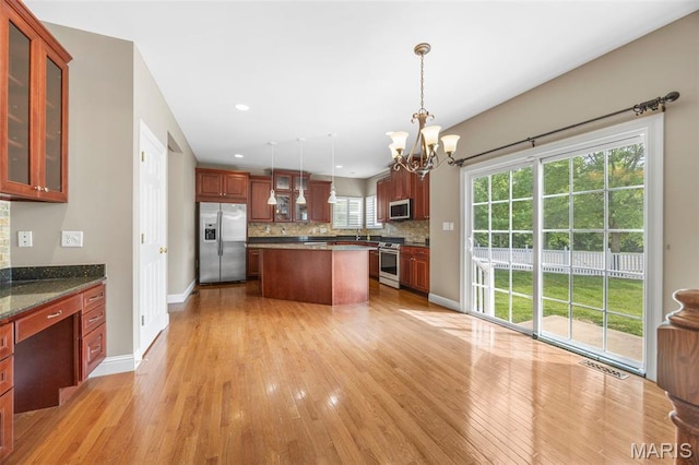 102 Riparian Dr, Ofallon, MO 63368 - kitchen with stainless steel appliances, a chandelier, light wood-style floors, decorative backsplash, and a kitchen island