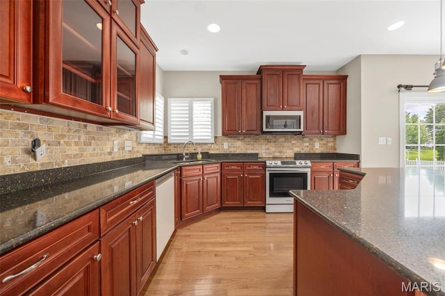 102 Riparian Dr, Ofallon, MO 63368 - kitchen with appliances with stainless steel finishes, a sink, light wood-style flooring, dark stone countertops, and recessed lighting