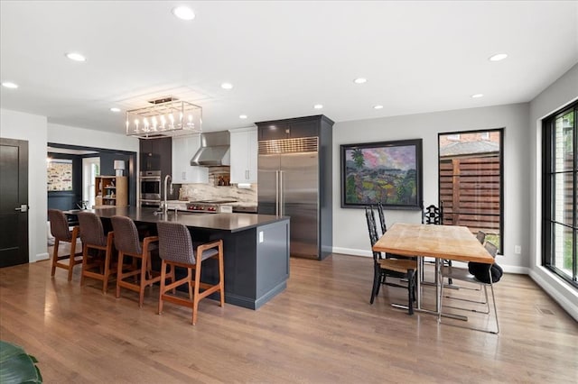 8033 Seminole Dr, Clayton, MO 63105 - kitchen with appliances with stainless steel finishes, wall chimney exhaust hood, plenty of natural light, dark countertops, and recessed lighting