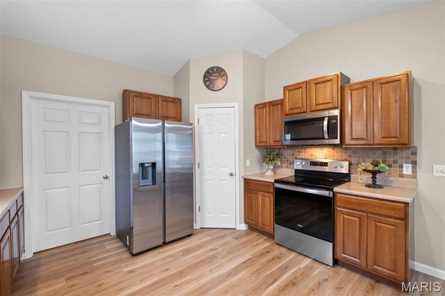171 Majestic Lakes Blvd, Moscow Mills, MO 63362 - kitchen featuring stainless steel appliances, backsplash, light wood-style flooring, light countertops, and lofted ceiling